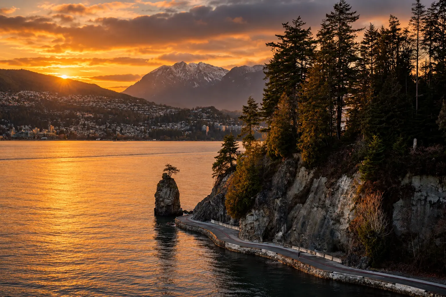 Sunset over Siwash Rock and the Stanley Park seawall, with the North Shore mountains beyond